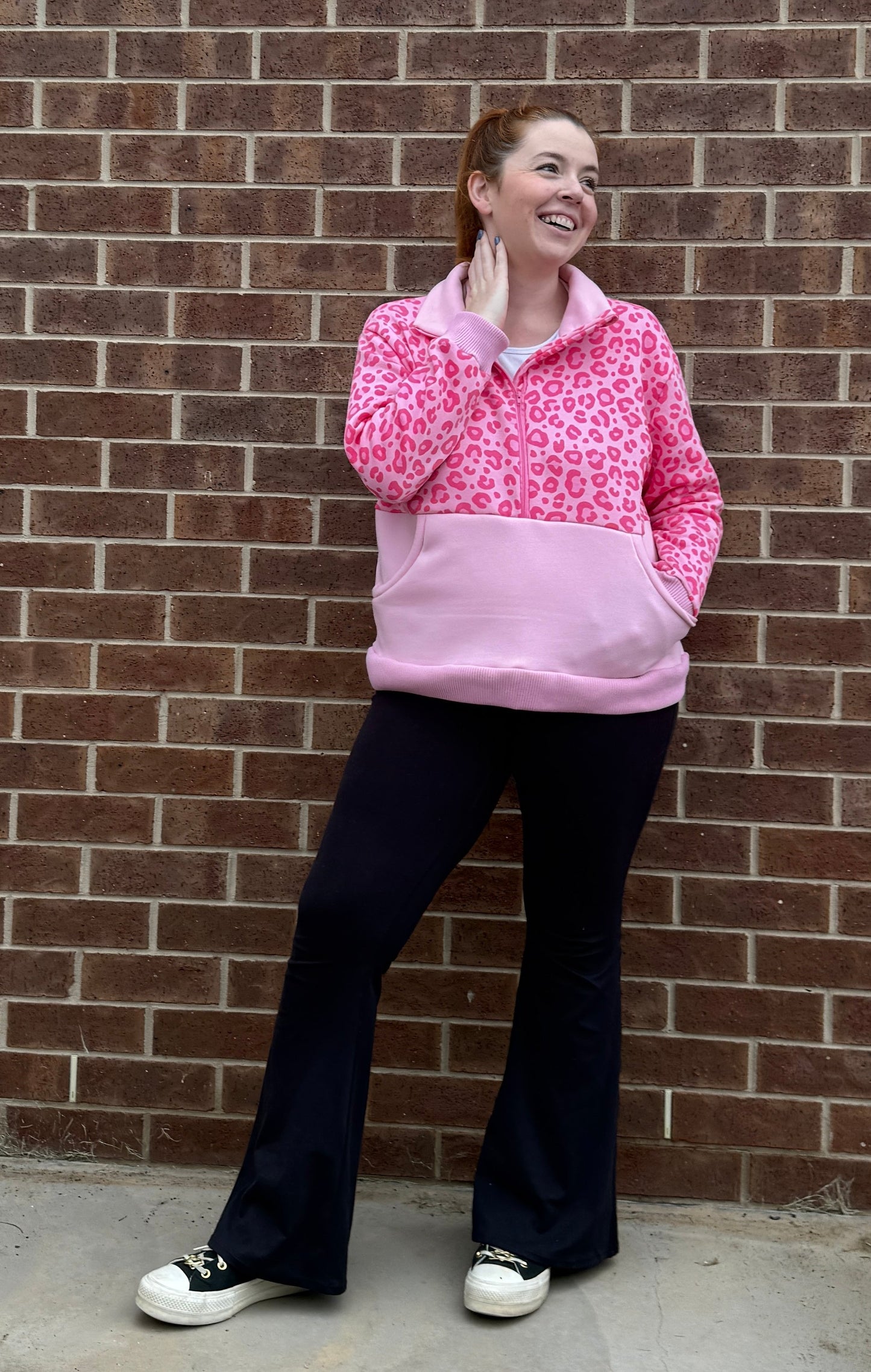 Person wearing a pink and white patterned jumper against a brick wall