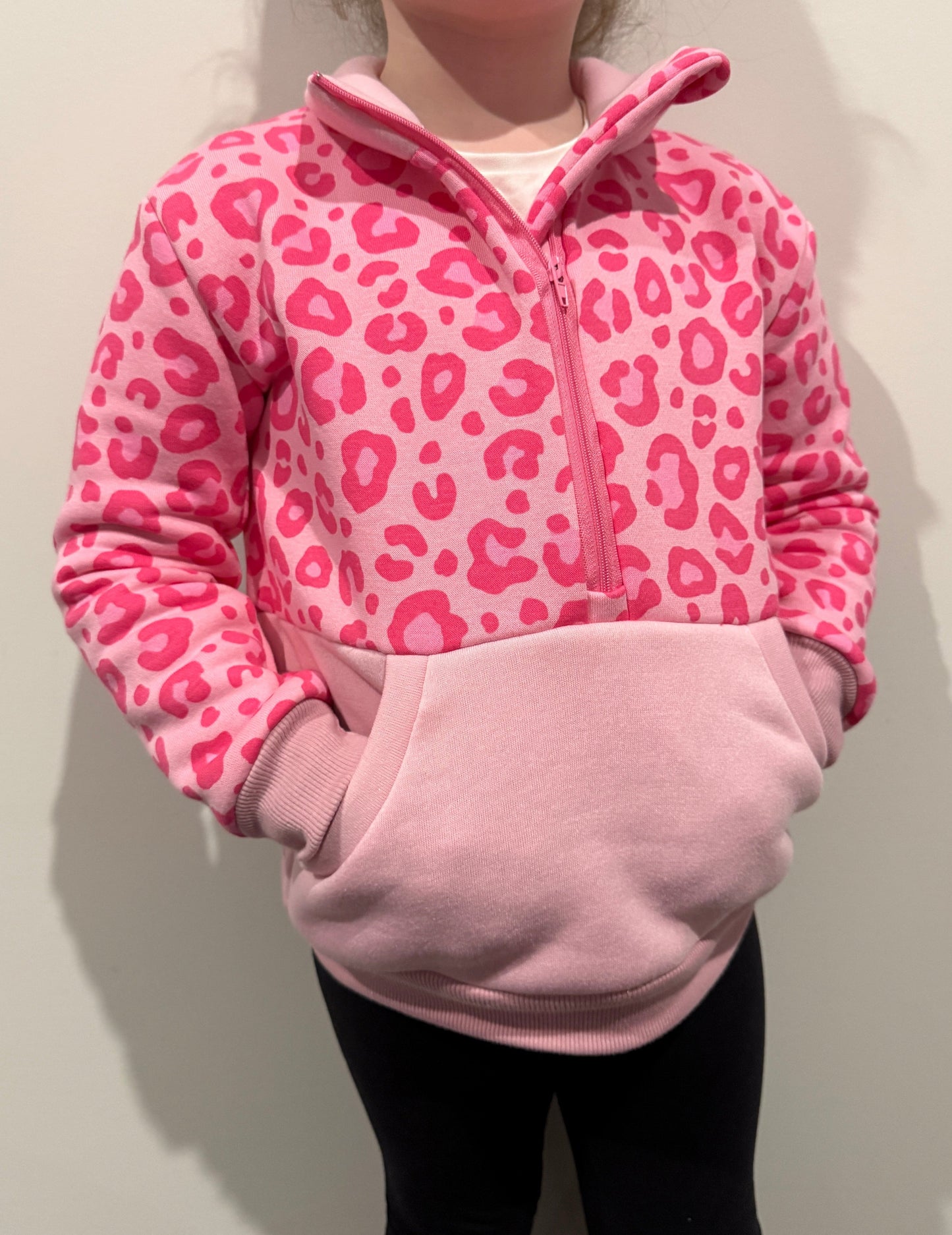 Child wearing a pink leopard print jumper on a light background