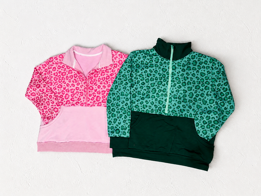 Two leopard print sweatshirts, one pink and one green, on a white textured background.