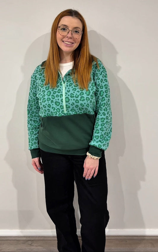 Person wearing a green leopard print jacket against a plain background