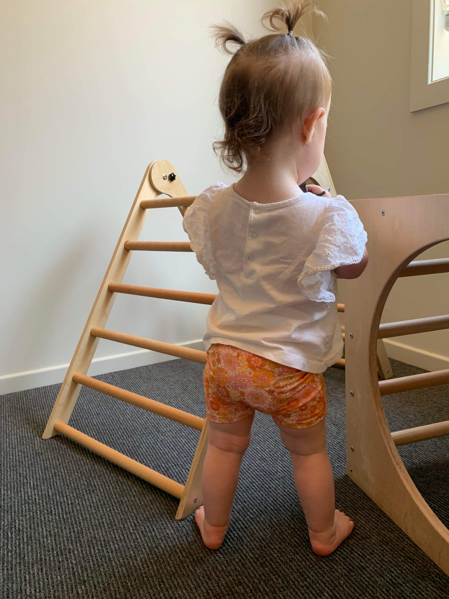 toddler wearing bike shorts that are a orange retro floral pattern