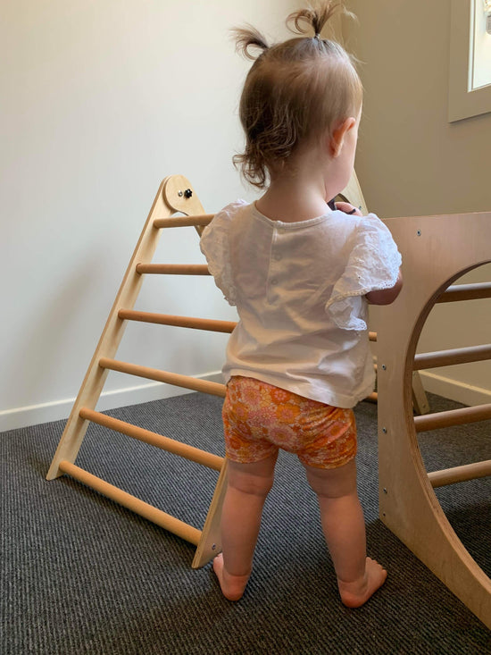 toddler wearing bike shorts that are a orange retro floral pattern